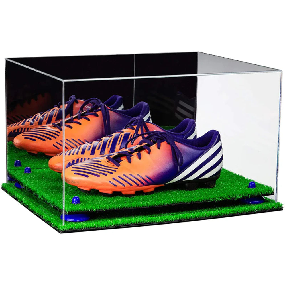 Orange and purple soccer cleats in a clear display case on grass