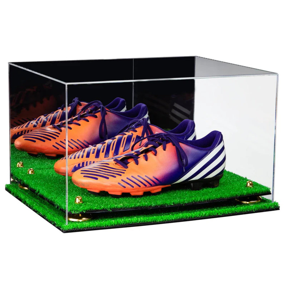 Clear display case with orange and purple soccer cleats on a grass-like surface