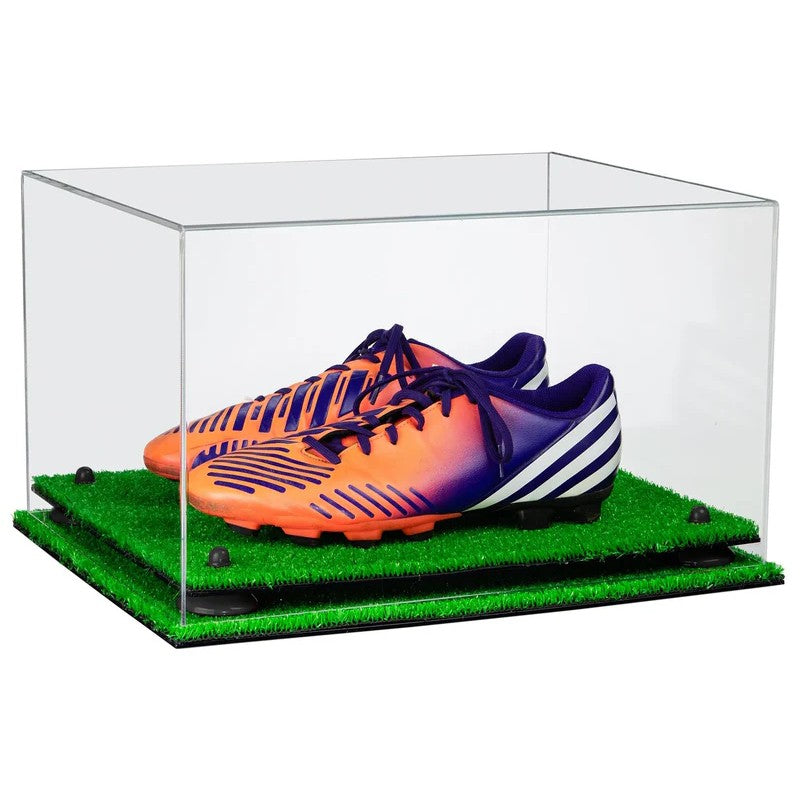 Orange and purple soccer cleats in a clear display case with grass base.
