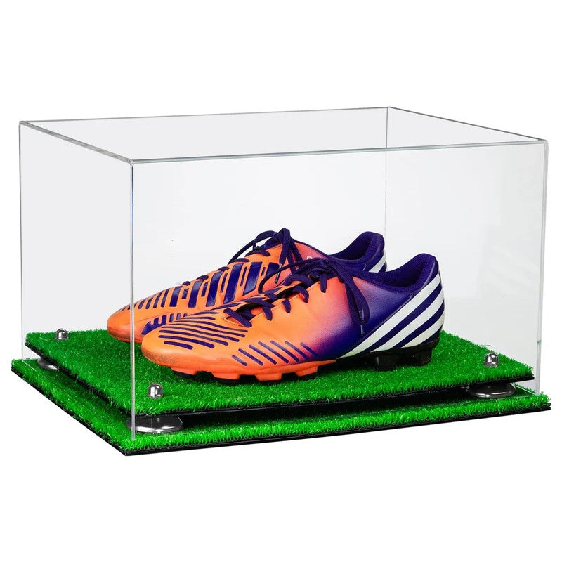 Clear display case with orange and purple soccer cleats on a green grass-like surface