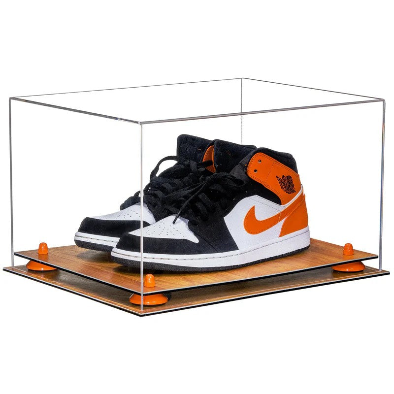 Black and orange sneakers in a clear display case on a white background