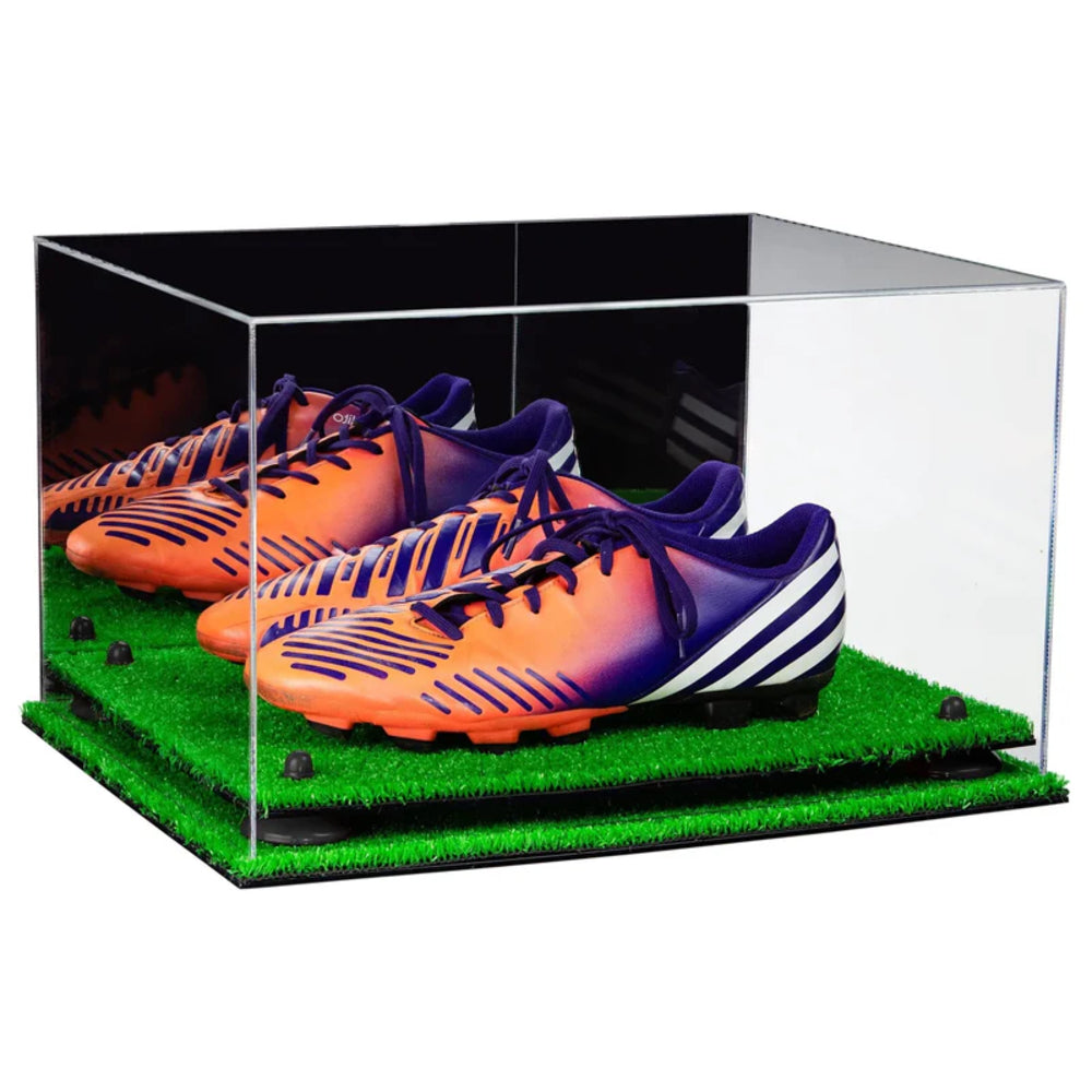 Pair of orange and purple soccer cleats in a clear display case with grass base.