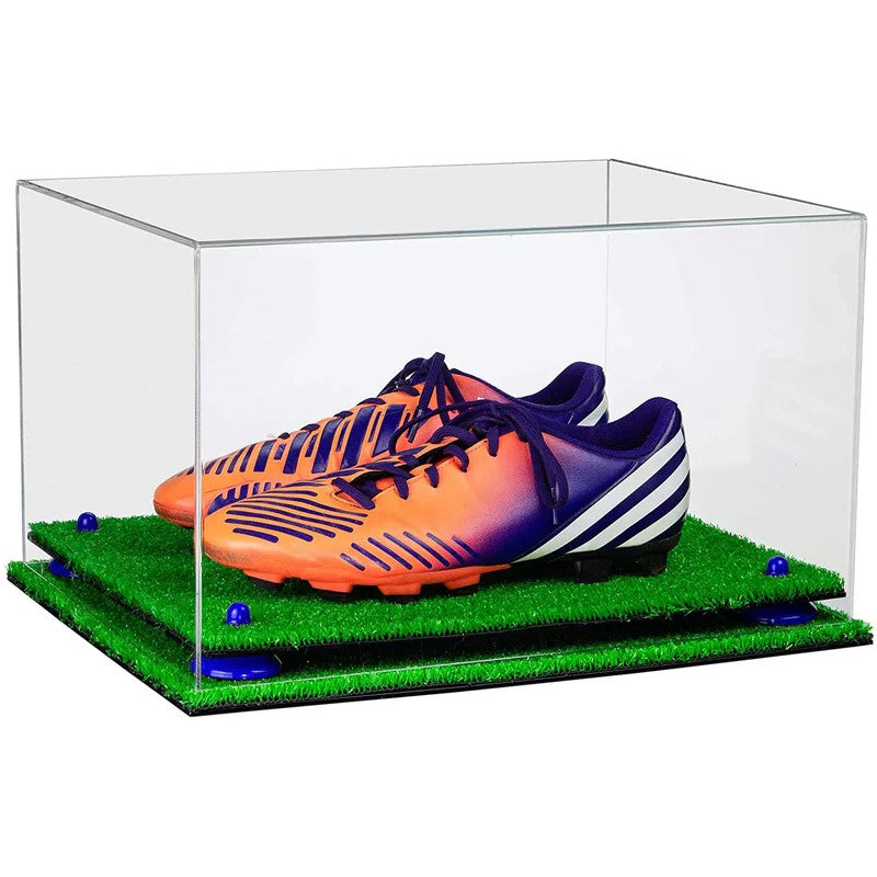Orange and purple soccer cleats in a clear display case with grass base.
