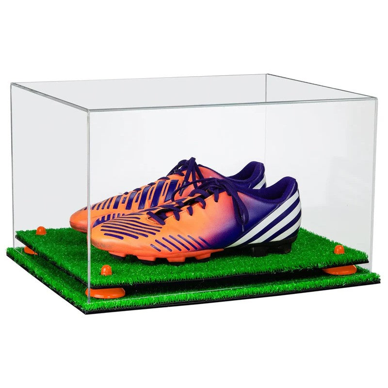 Clear display case with orange and purple soccer shoes on a green grass-like surface