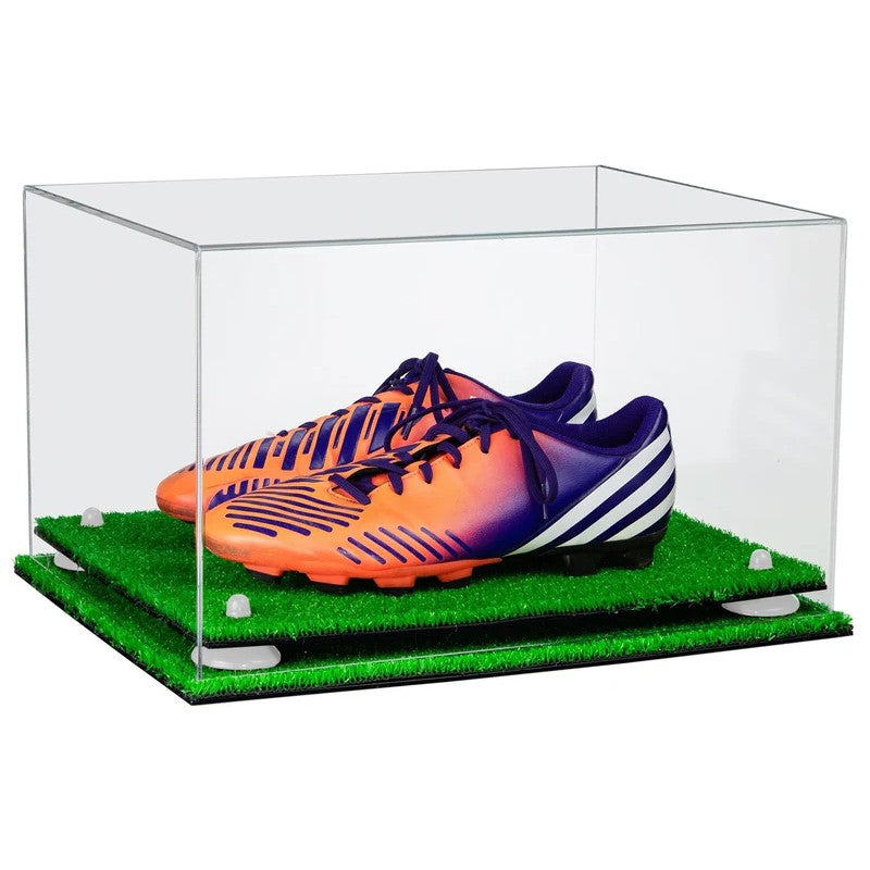 Clear display case with orange and purple soccer cleats on a green grass-like surface